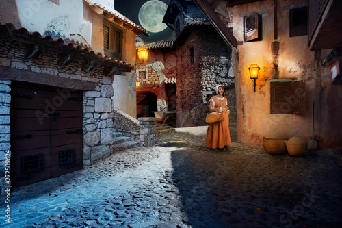 Night street of a medieval city illuminated by lanterns and moonlight
