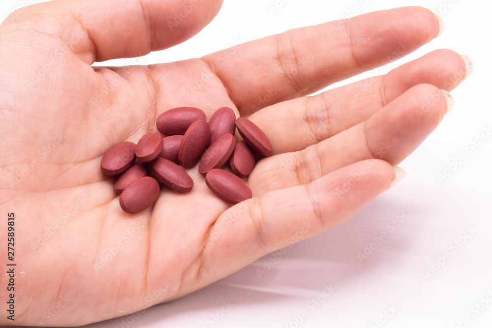 Ferrous Fumarate pills with Vitamins for treat iron deficiency anemia in hand on white background. Ferrous Fumarate pills with Vitamins for treat iron deficiency anemia in hand on white background.