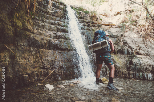 Single traveller man standing near Great Falls Shulamit falling into a shallow pond with emerald water. Ein Gedi - Nature Reserve and National Park, Israel. Extreme and adventure tours in Israel. photo