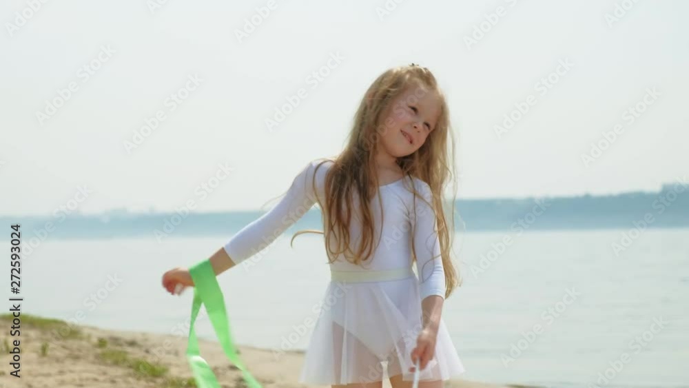 preschool girl with dances a gymnastic ribbon on a sandy beach. Summer, dawn preschool girl with dances a gymnastic ribbon on a sandy beach. Summer, dawn