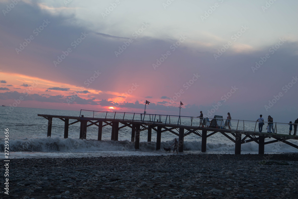 over Batumi beach Jetty, as powerful waves roll in, and a very colorful sky is reflected on the beach. sunset on the city embankment