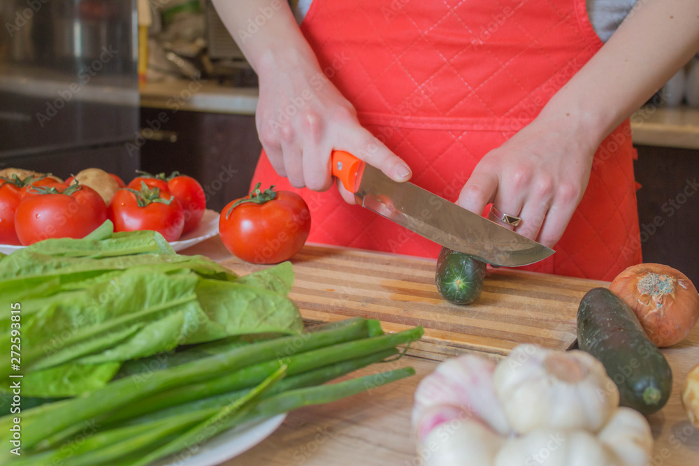 Chef cuts the vegetables into a meal. A woman uses a knife and cooks. Woman's hands cutting vegetables, behind fresh vegetables Chef cuts the vegetables into a meal. A woman uses a knife and cooks. Woman's hands cutting vegetables, behind fresh vegetables