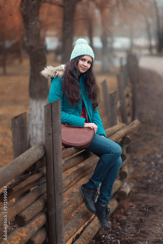 Woman in hat is sitting on the wooden fence Woman in hat is sitting on the wooden fence