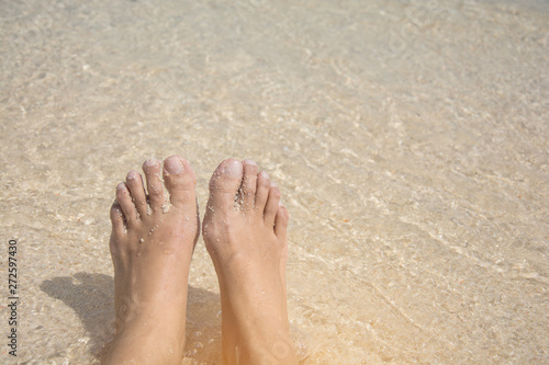 Wet bare foot of female reach to the beach in shallow sea for relaxing.