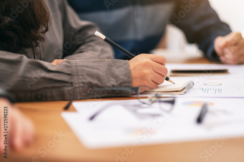 A businesswoman writing on notebook and working on business data and document on the table in office
