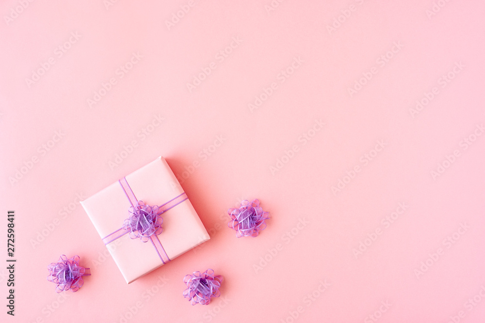 Pink gift box with ribbon and bow on color background and space for text. Top view