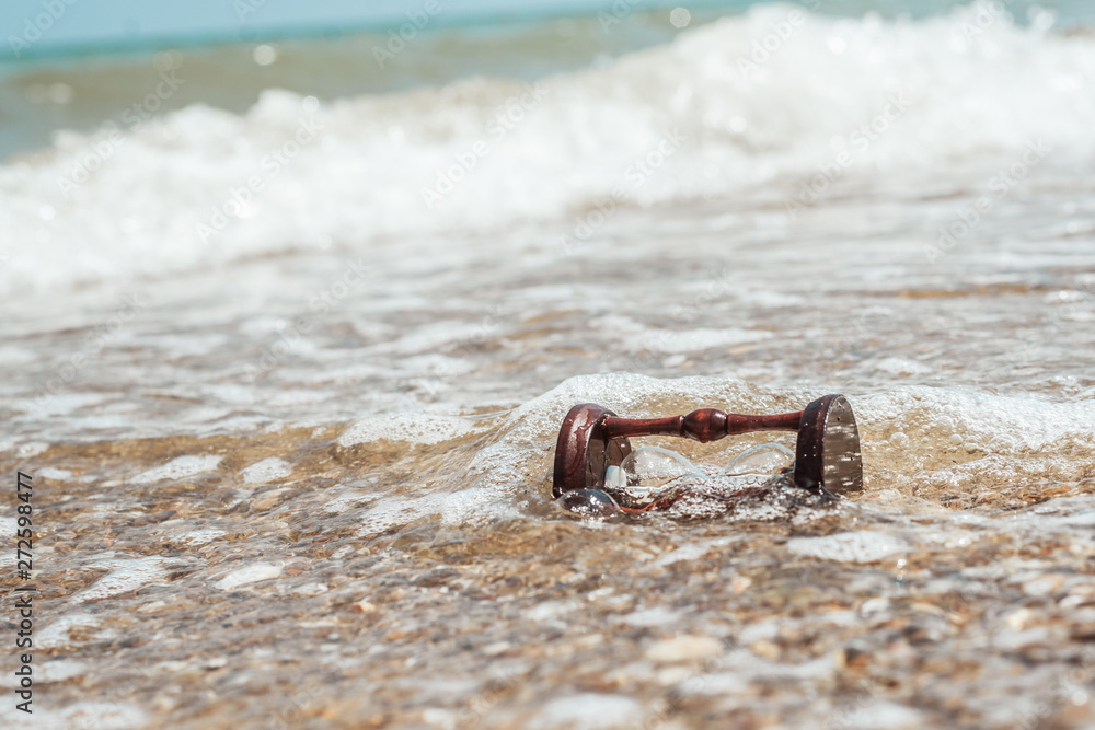 Fototapeta premium Hourglass on the beach, ocean. The concept of transience of time.