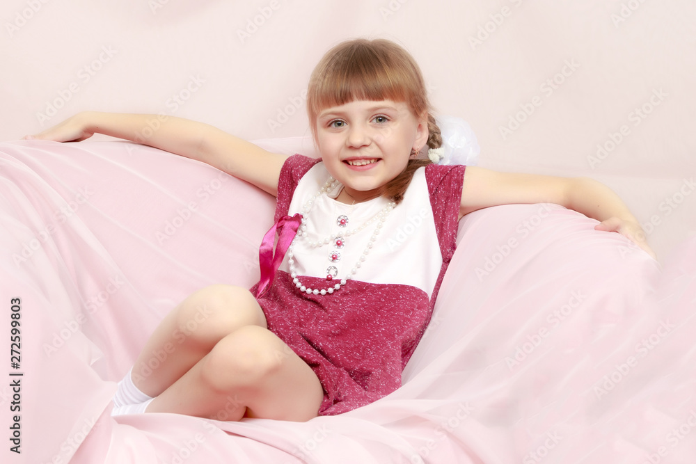 Girl sits on a pink sofa. Girl sits on a pink sofa.