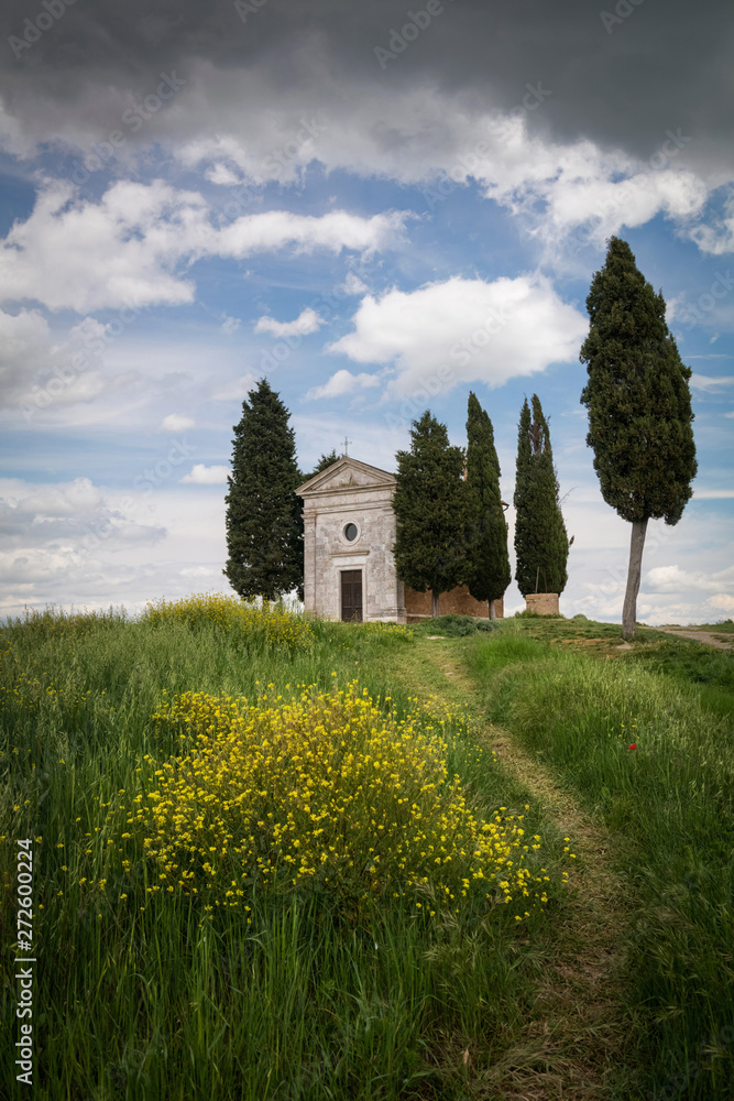 Cappella Di Vitaleta or Vitaleta Chapel near San Quirico D'Orcia in Tuscany. Yellow rapeseed flowers with the famous Chapel on background