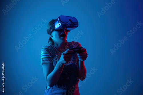 Young cute girl playing vr with gamepad. with creative blue-red light. Emocyanally and fun.concept gaming