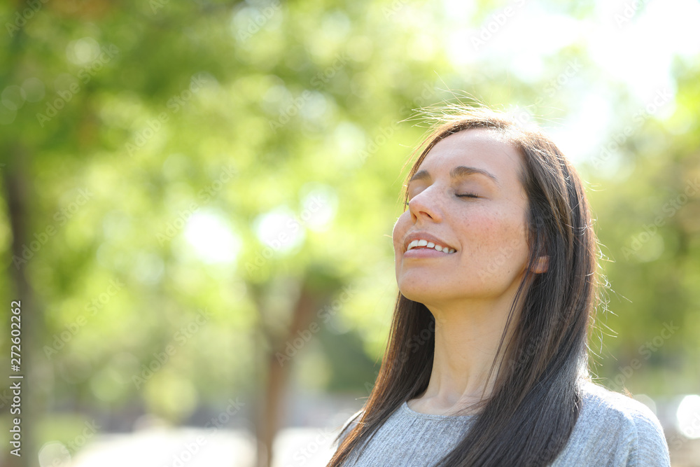 Happy woman breathing fresh air in a park or forest