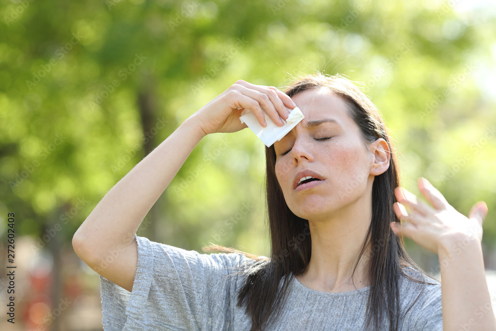 Woman drying sweat using a wipe in a warm summer day Woman drying sweat using a wipe in a warm summer day