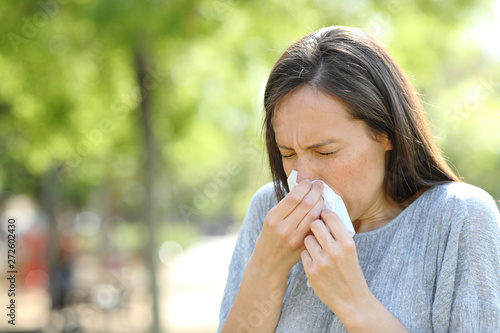 Woman sneezing using a wipe in a park