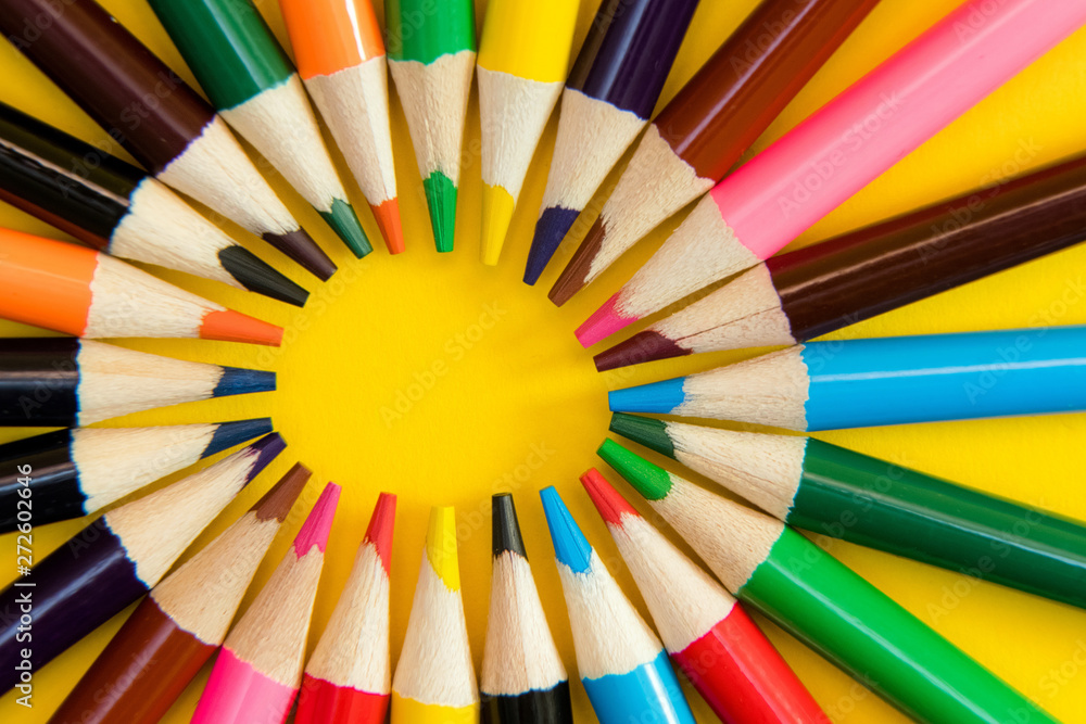 An assortment of colour pencils in circle, spiral on yellow back An assortment of colour pencils in circle, spiral on yellow back