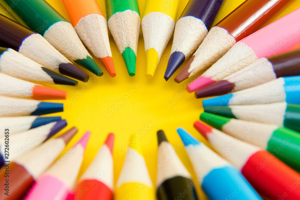 An assortment of colour pencils in circle, spiral on yellow back An assortment of colour pencils in circle, spiral on yellow back