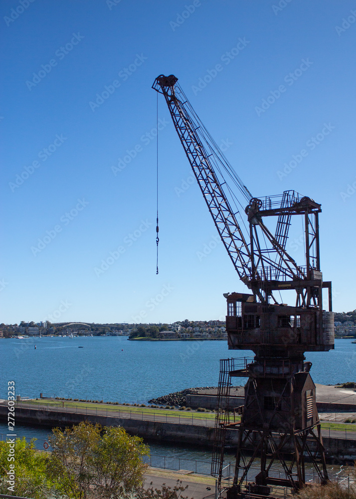 Industrial crane set dockside on Cockatoo Island Sydney Harbour Australia against blue water and sky