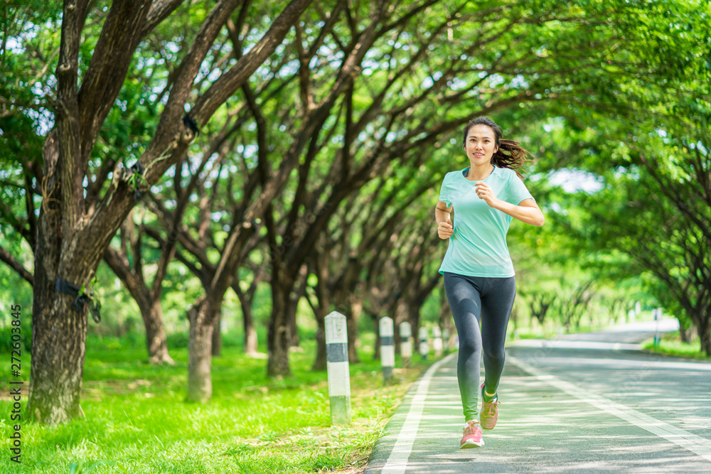 Young asian woman running on road in the nature.