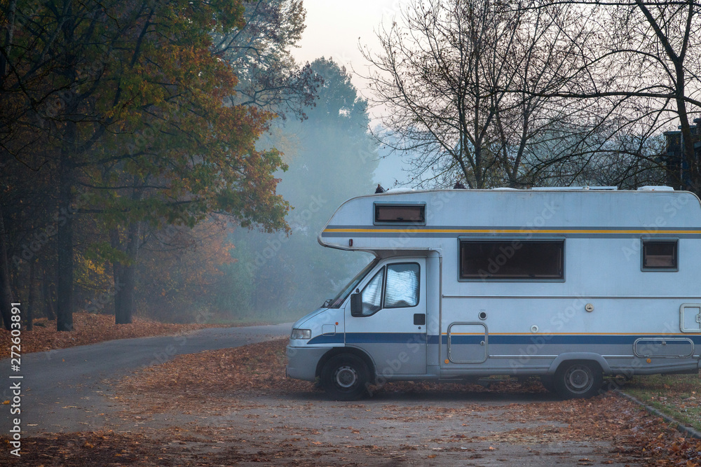 Old camper van parked in next to the road on foggy and cold autu