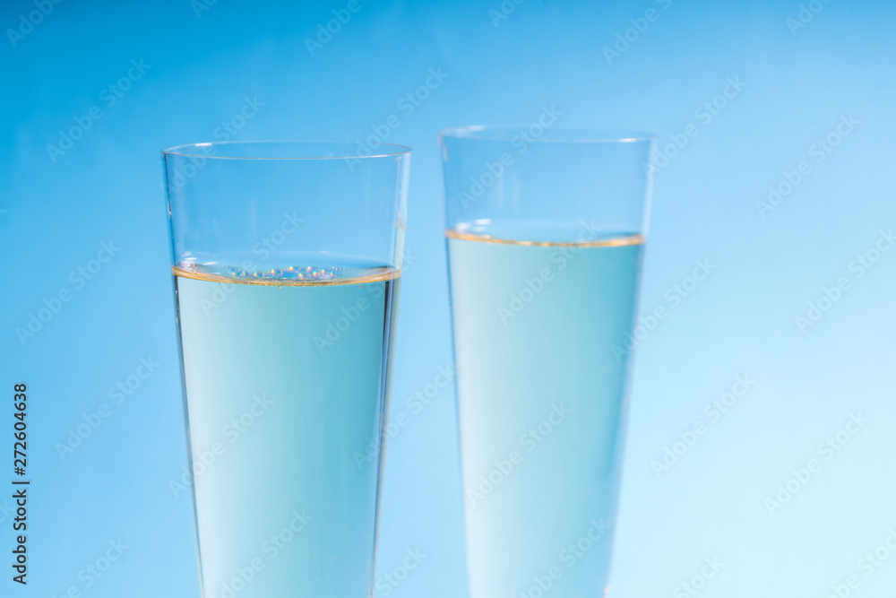 Close up of two glasses of champagne isolated on a blue backgrou Close up of two glasses of champagne isolated on a blue backgrou