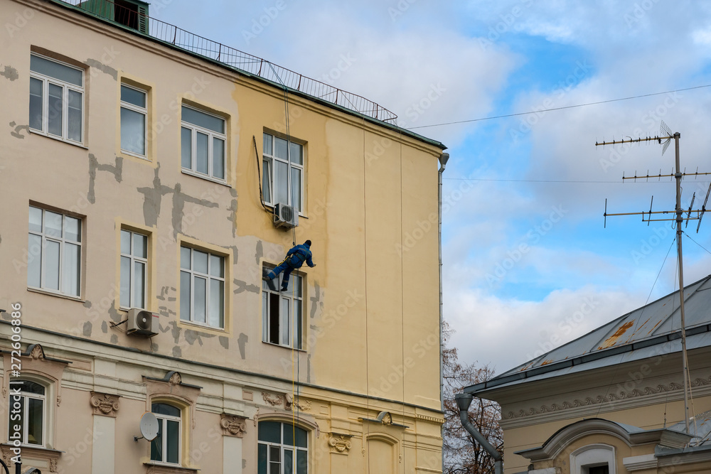MOSCOW - OCTOBER 27, 2018: A working painter - a mountaineer is painting a residential building MOSCOW - OCTOBER 27, 2018: A working painter - a mountaineer is painting a residential building