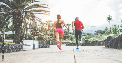 Couple of fitness friends running outdoor - Joggers people training at evening time after work - Jogging, healthy lifestyle and sport concept - Main focus on woman body