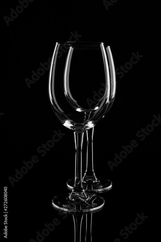 Two empty transparent wine glasses, isolated on black background