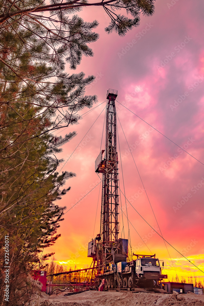 Drilling a deep well mobile drilling rig in an oil and gas field. The field is located in the Far North in the taiga. Beautiful dramatic sunset sky in the background.