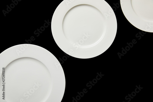 top view of white empty round plates isolated on black
