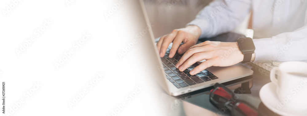 Cropped image of a young man working on his laptop, man hands busy using laptop at office desk. Young businessman working with laptop at office. Copy space