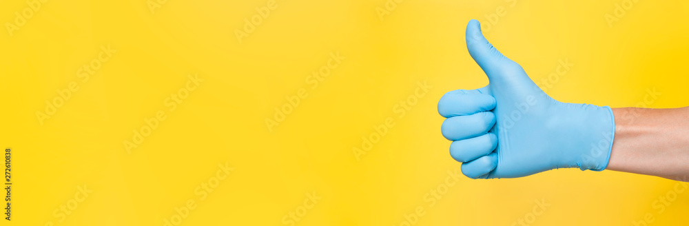 Doctor Wearing Blue Latex Glove Giving Thumbs Up Sign. Yellow background. Copy space - obrazy, fototapety, plakaty 