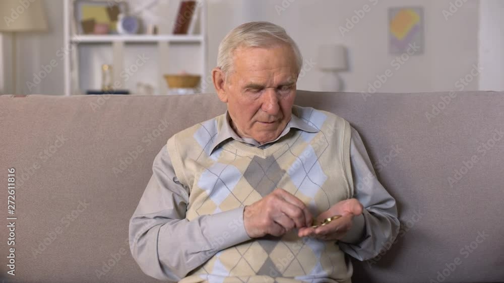 Sad aged man sitting on sofa and counting coins in palm, social insecurity Sad aged man sitting on sofa and counting coins in palm, social insecurity
