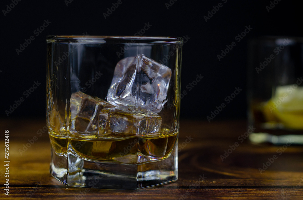 Whiskey / cognac glass with ice on a wooden background. Dark backdrop Whiskey / cognac glass with ice on a wooden background. Dark backdrop