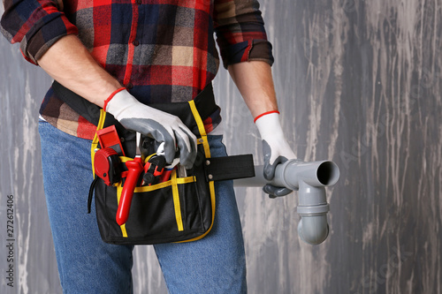 Plumber with tools belt on grunge background, closeup