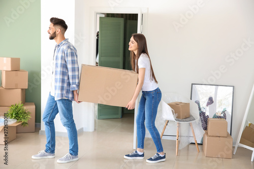 Young couple with big box in their new house