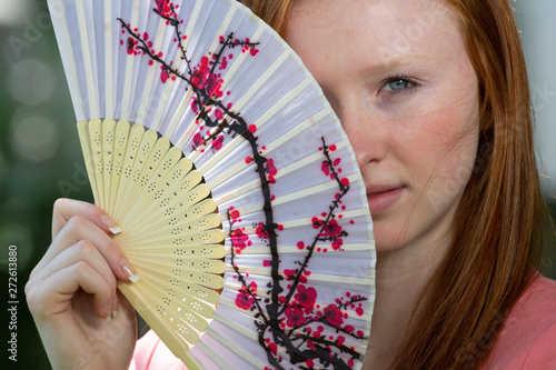 young girl with hand fan outside