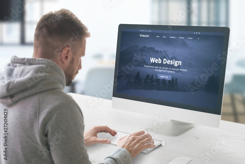 Web design studio concept with man and computer display with modern web site presentation. photo