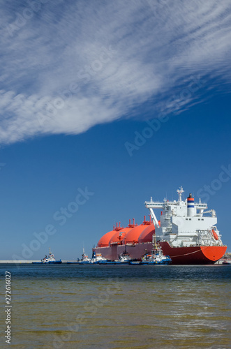 RED LNG TANKER AND A SWARM OF TUGBOATS - A giant ship moored to the gas terminal in Swinoujscie