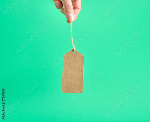 female hand holding a paper brown blank tag on a rope photo