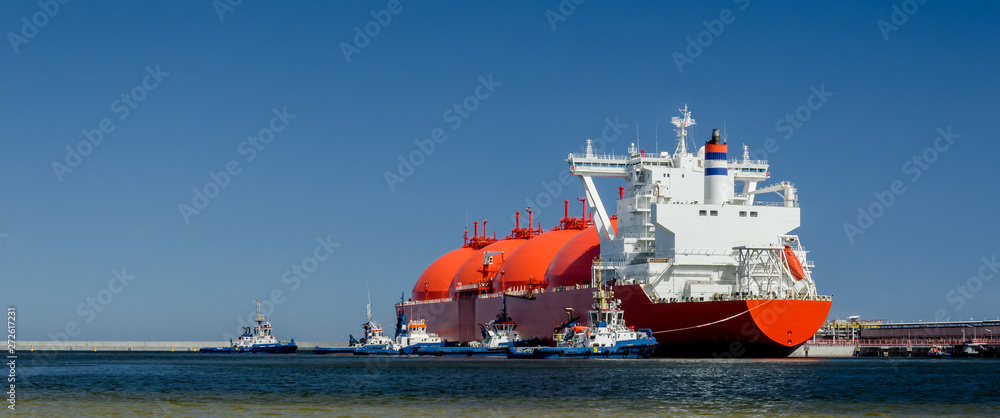 Fotografía RED LNG TANKER AND SWARM OF TUGBOATS - A giant ship moored to the gas terminal i