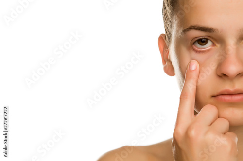 Young woman pulling her lower eyelid with her finger on white background photo