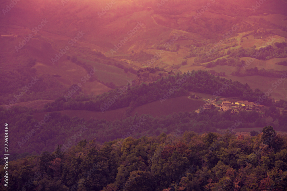 Beautiful landscape of mountains and rural town under blue fog sky from high view of San Marino city. Violet color