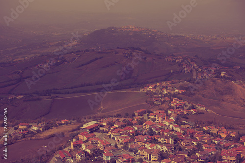 Beautiful landscape of mountains and rural town under blue fog sky from high view of San Marino city. Violet portrait