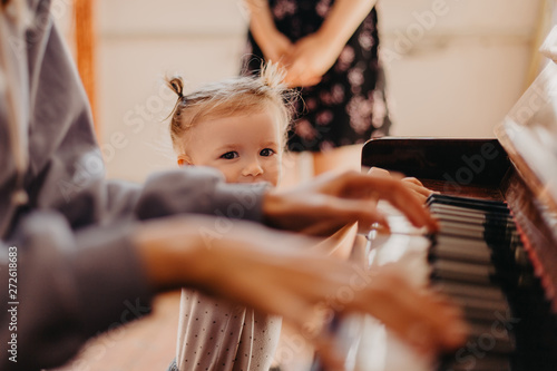 Cute little happy child girl playing piano in a light room. Selective focus, noise effect