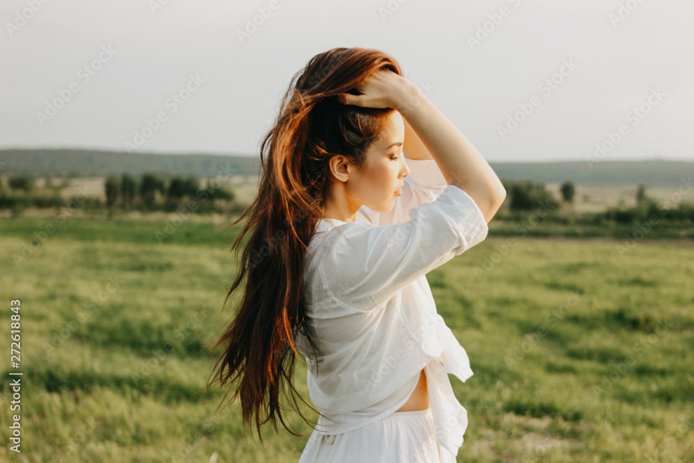 Portrait of beautiful carefree long hair girl in white clothes on field at sunset. Sensitivity to nature concept Portrait of beautiful carefree long hair girl in white clothes on field at sunset. Sensitivity to nature concept