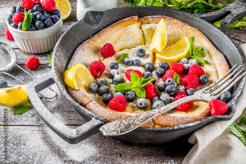 Sweet breakfast vegan dutch baby baked pancake with fruit and berries  wooden background copy space