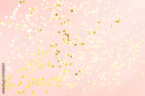 Holographic stars and gold sparkles on pastel pink background. Festive backdrop for your projects