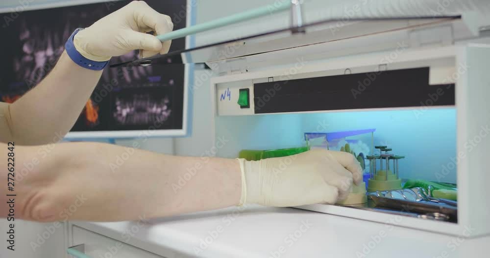 Close up of dentist hand in gloves taking tips for dental instruments from sterile box. Close up of dentist hand in gloves taking tips for dental instruments from sterile box.