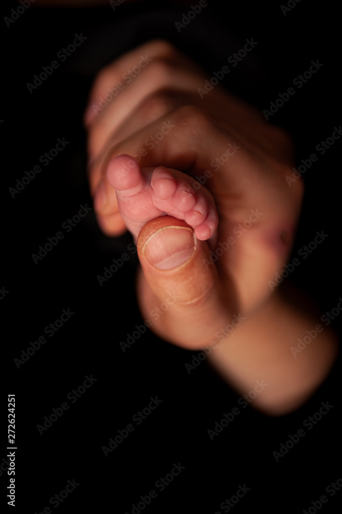 father holds his newborn daughter's leg