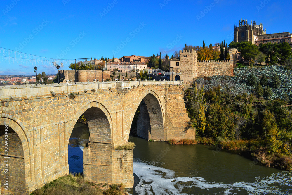 Ancient stone bridge with arches across the river Tagus in Toledo.