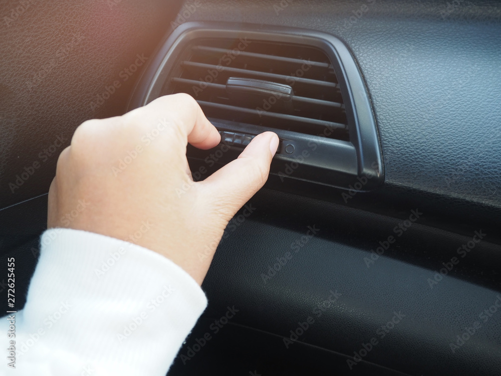 Woman hand using control car air conditioning system grid panel on console with sunlight, copy space.